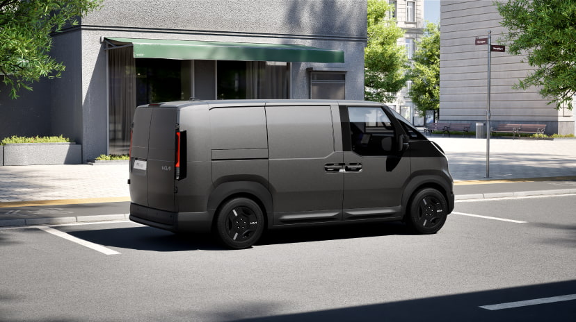 Seitenansicht des Kia PV5 Cargo beim Fahren in einer städtischen Umgebung, die seine stromlinienförmige Karosserie und praktische Form zeigt